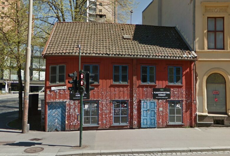 Bildet viser et slitt, rødt hus med blå dører på et gatehjørne i Oslo